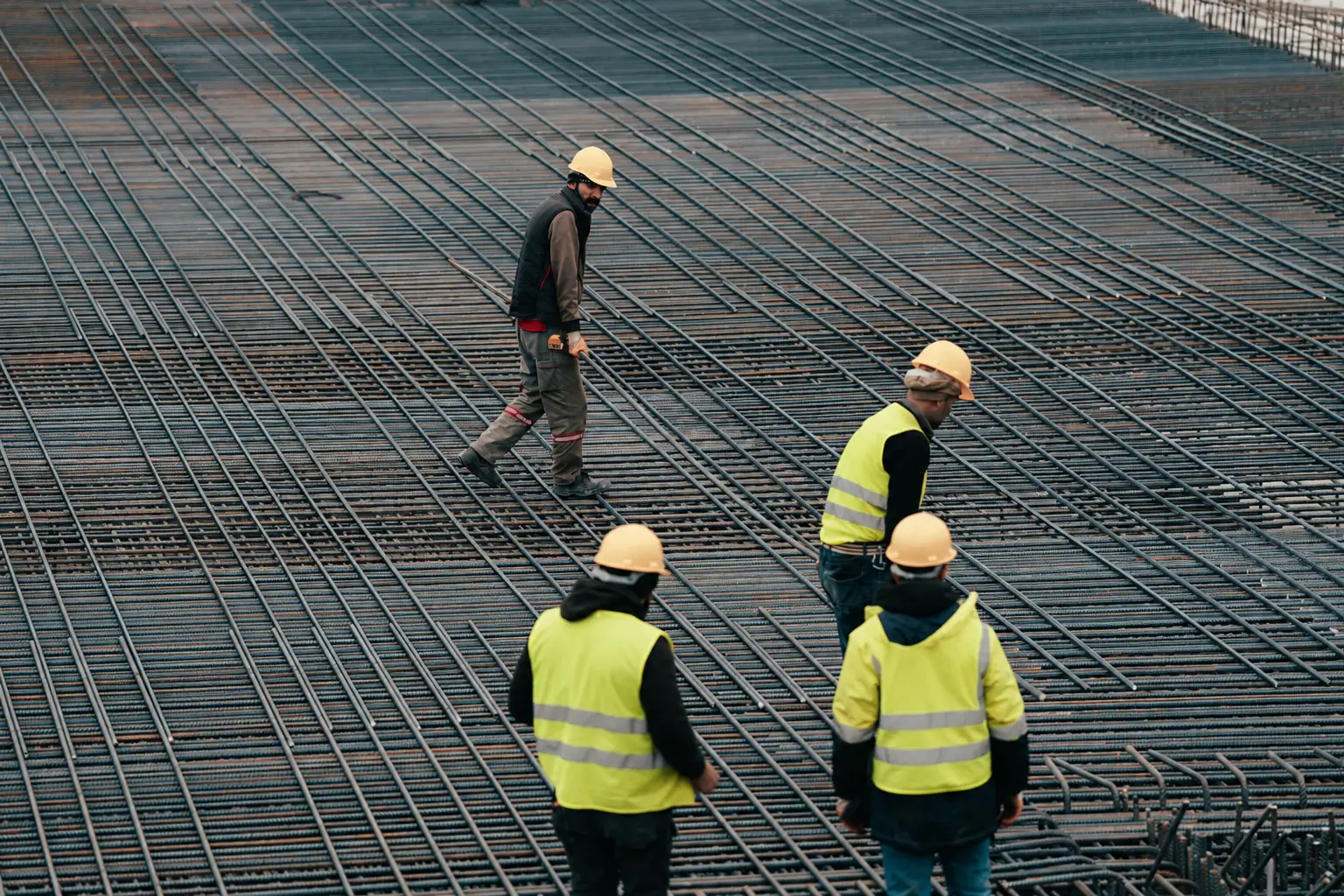 Equipo de trabajadores con casco y chaleco sobre el armado de acero de una obra