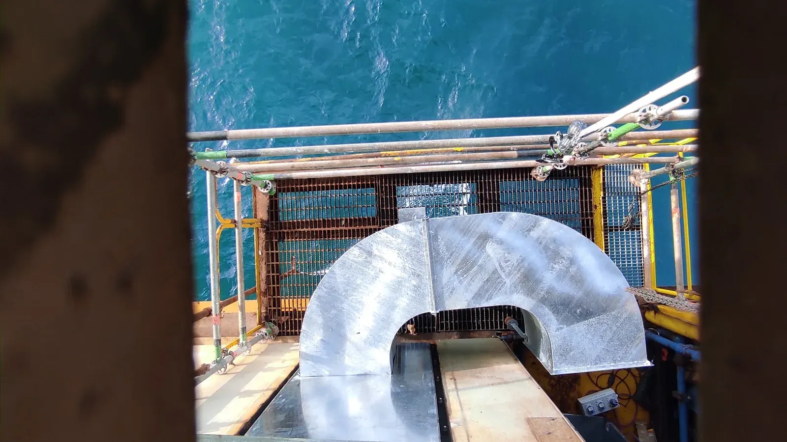 Codo de ducto de ventilación metálico montado en el borde de la plataforma offshore AM-6, con el mar de fondo